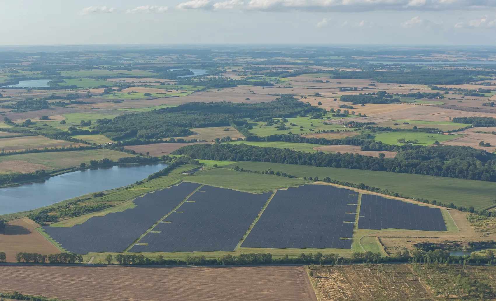 A ground-mounted solar field in a northern European agricultural landscape